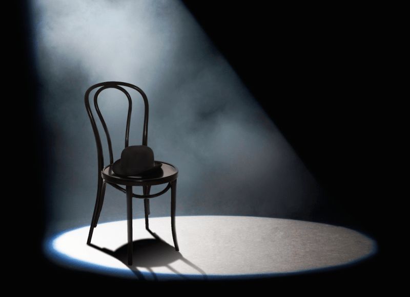 A metal-framed chair sitting in a spotlight.